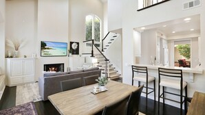 Un salón amplio con chimenea, una mesa de comedor y una escalera que lleva a un nivel superior.