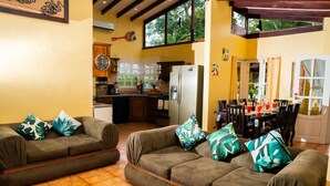A living room with two sofas, a dining area with a table and chairs, and a kitchen in the background.