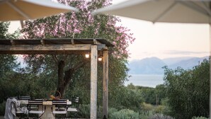Zona de piscina con pérgola, mobiliario exterior y vistas a montañas.