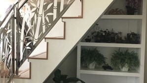 A staircase with a bamboo-patterned railing, leading to a white shelving unit with various potted plants. - Crystal Palace Hotel (Yangon)