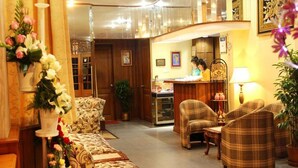 A hotel lobby with a sofa, chairs, a reception desk, and a dining area. - Crystal Palace Hotel (Yangon)