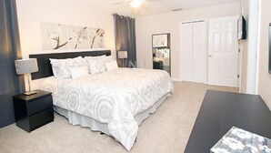 A bedroom with a bed, nightstands, a desk, a ceiling fan, and artwork on the walls. - Fv62884 - Regal Oaks - 4 Bed 3.5 Baths Townhome (Kissimmee)