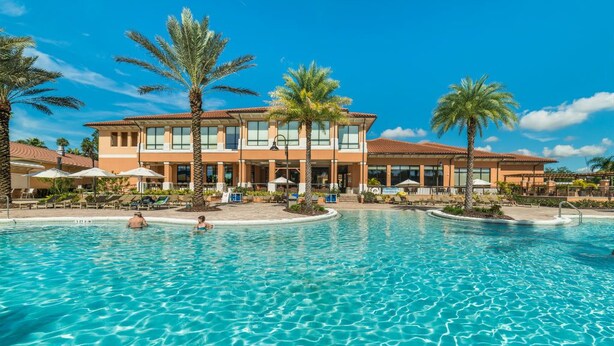A hotel with a large swimming pool, palm trees, and outdoor seating areas. - Fv62884 - Regal Oaks - 4 Bed 3.5 Baths Townhome (Kissimmee)