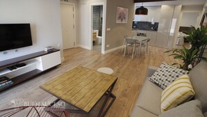 En moderne stue med et fladskærms-tv, et træ sofabord og en sofa med mønstrede puder.