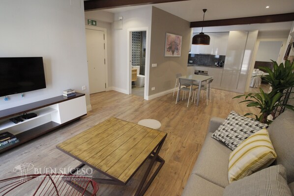A modern living room with a flat-screen TV, wooden coffee table, and a sofa with patterned cushions. - Free WIFI / AC Buen Suceso Apartment, right in the city center, at Metropol square (Sevilla)