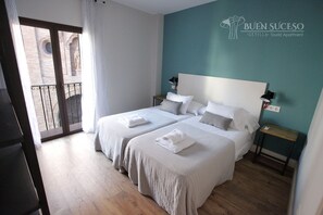 A hotel room with two beds, a balcony with a view of a building, and a teal accent wall. - Free WIFI / AC Buen Suceso Apartment, right in the city center, at Metropol square (Sevilla)