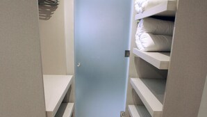 En smal gang med en dør i enden, med hylder fyldt med foldede håndklæder på hver side.