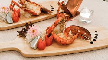 Two lobster halves on wooden serving boards with garnishes and a glass of water.
