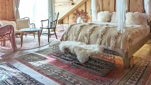Une chambre à coucher avec un lit à baldaquin, des murs en bois, une lampe suspendue et un décor de style rustique.
