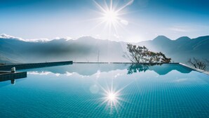 Un ciel d’un bleu éclatant, le soleil brillant au-dessus d’une piscine, le tout entouré de montagnes.