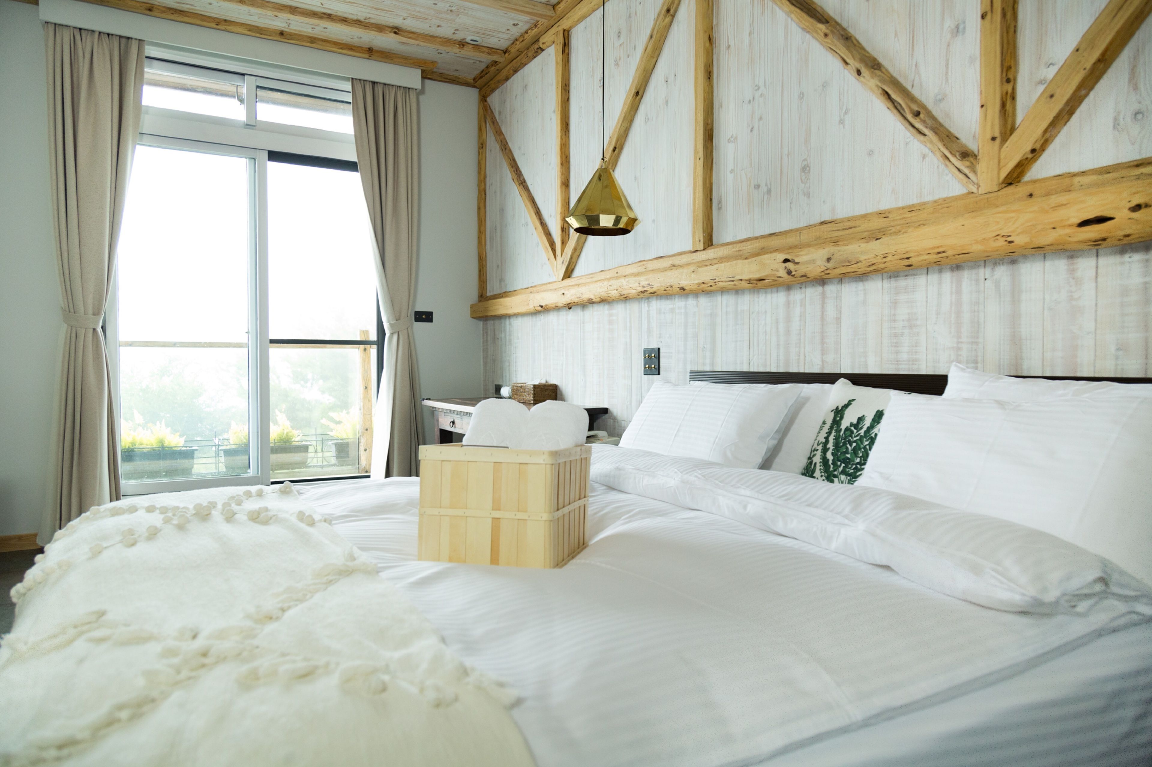 A large bed with white linens, a wooden headboard, and a wooden crate on the bed.