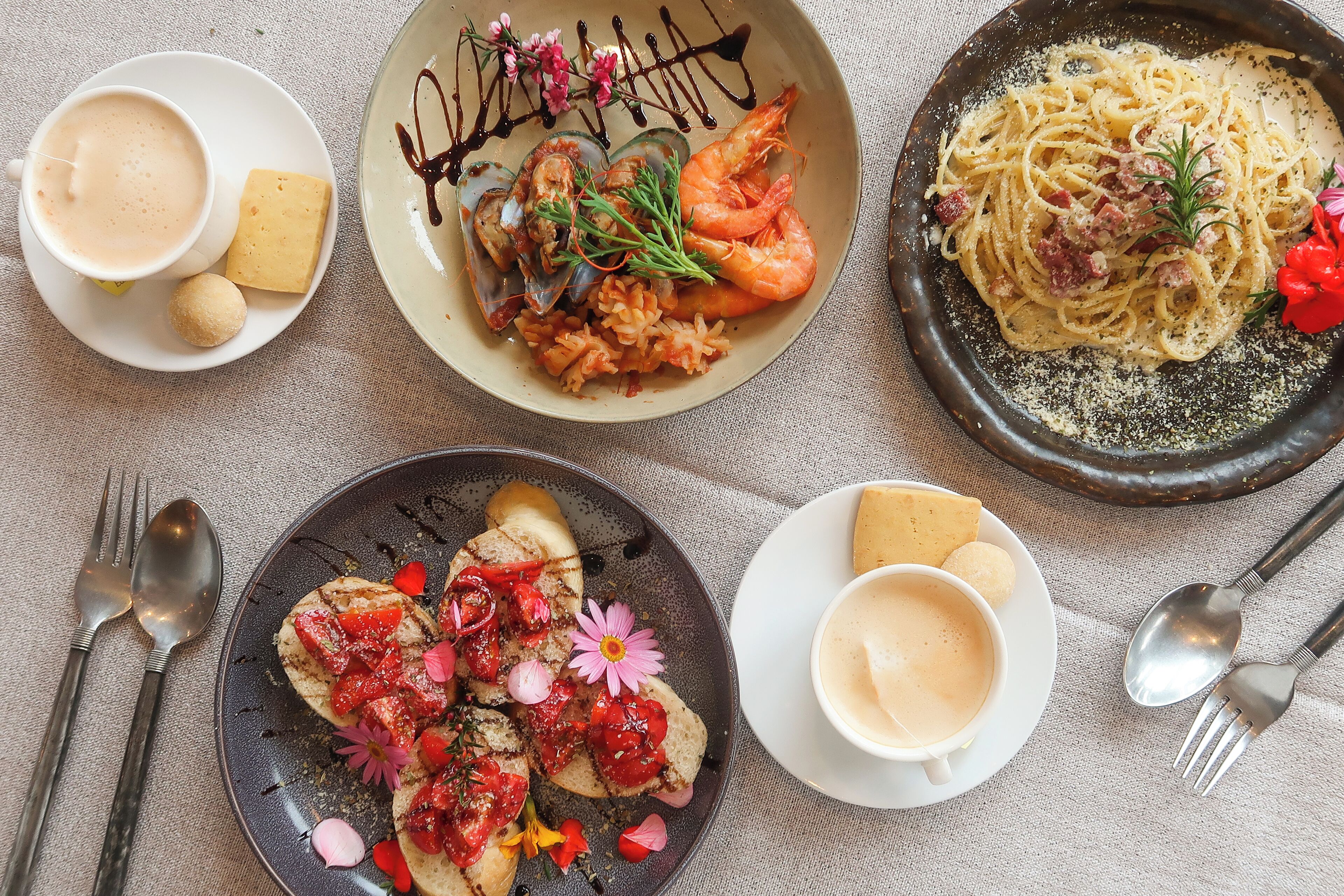 Una mesa con diferentes platos, incluyendo pasta, camarones y pan, además de tazas de café.