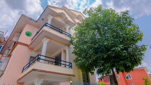 A multi-story building with a balcony, a tree in front, and a clear sky. - Lemon Tree Apartment and Homestay (Tohka)