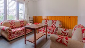 A living room with two sofas, a wooden table, and a window with curtains. - Lemon Tree Apartment and Homestay (Tohka)