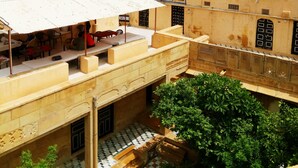 A hotel named 'Paradise' with a signboard, outdoor seating area, and a view of the surrounding landscape. - Hotel Paradise (Jaisalmer)