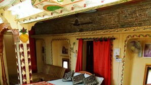 A room with two beds, a colorful striped rug, a patterned ceiling, and a small table with a phone. - Hotel Paradise (Jaisalmer)