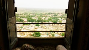 A room with a window seat featuring a plaid cushion and a patterned pillow. - Hotel Paradise (Jaisalmer)
