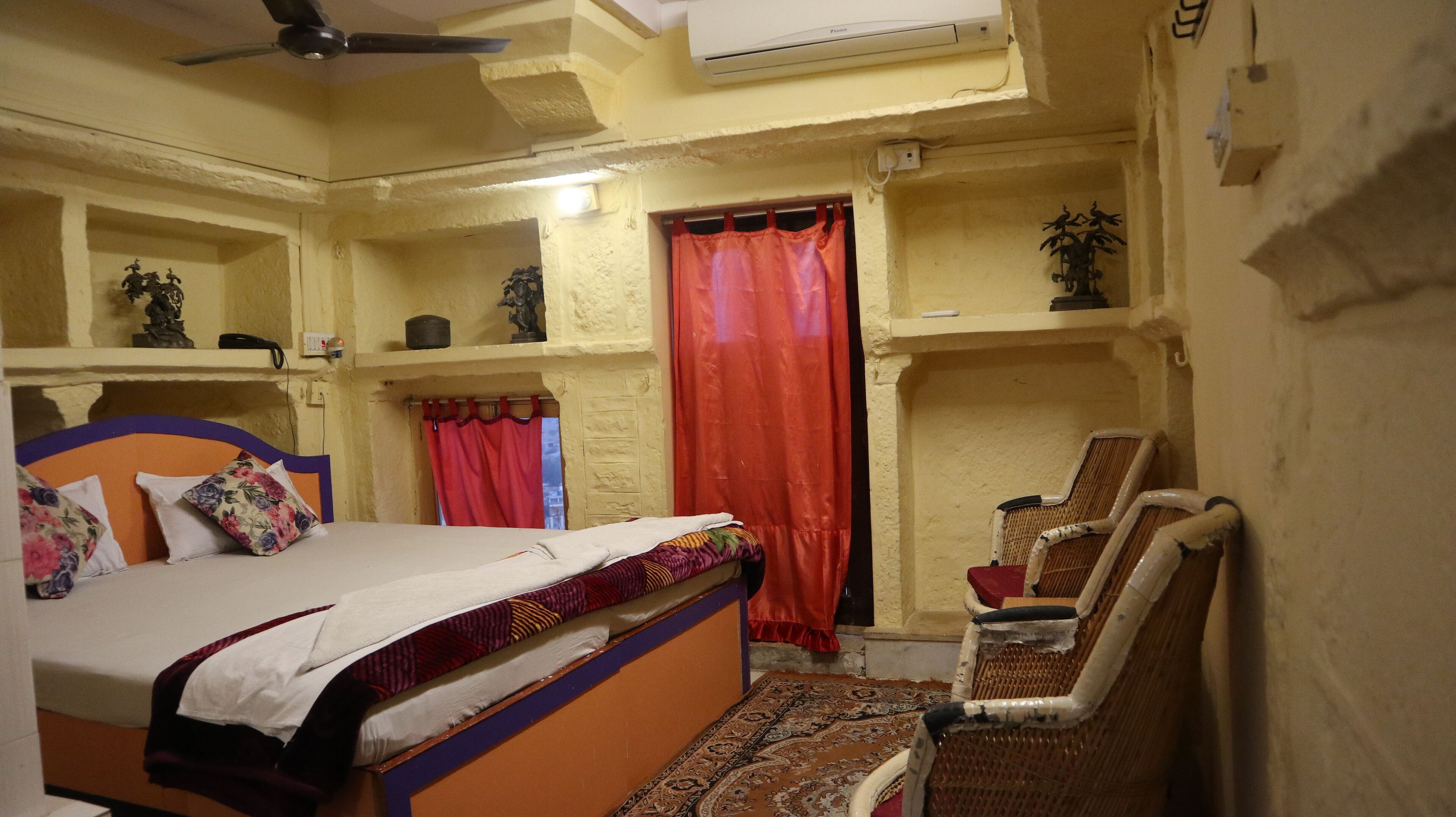 A bedroom with a bed, a chair, a shelf with decorative items, and a red curtain.