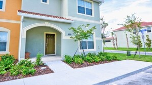 A two-story residential building with a front entrance, a small porch, and a landscaped front yard. - Fv50308 - Paradise Palms - 5 Bed 3 Baths Townhome (Kissimmee)