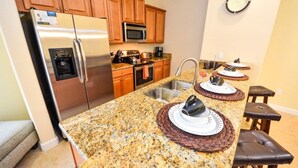 A kitchen with granite countertops, stainless steel appliances, wooden cabinets, and a built-in microwave. - Fv50308 - Paradise Palms - 5 Bed 3 Baths Townhome (Kissimmee)