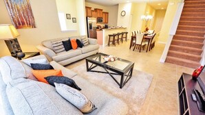 A living room with a sofa, coffee table, and a dining area with chairs and a table. - Fv50308 - Paradise Palms - 5 Bed 3 Baths Townhome (Kissimmee)