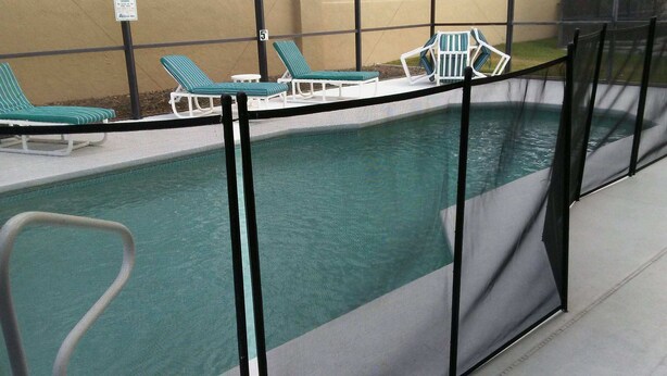 An indoor swimming pool with a safety fence, multiple lounge chairs, and a clear view of the pool area.