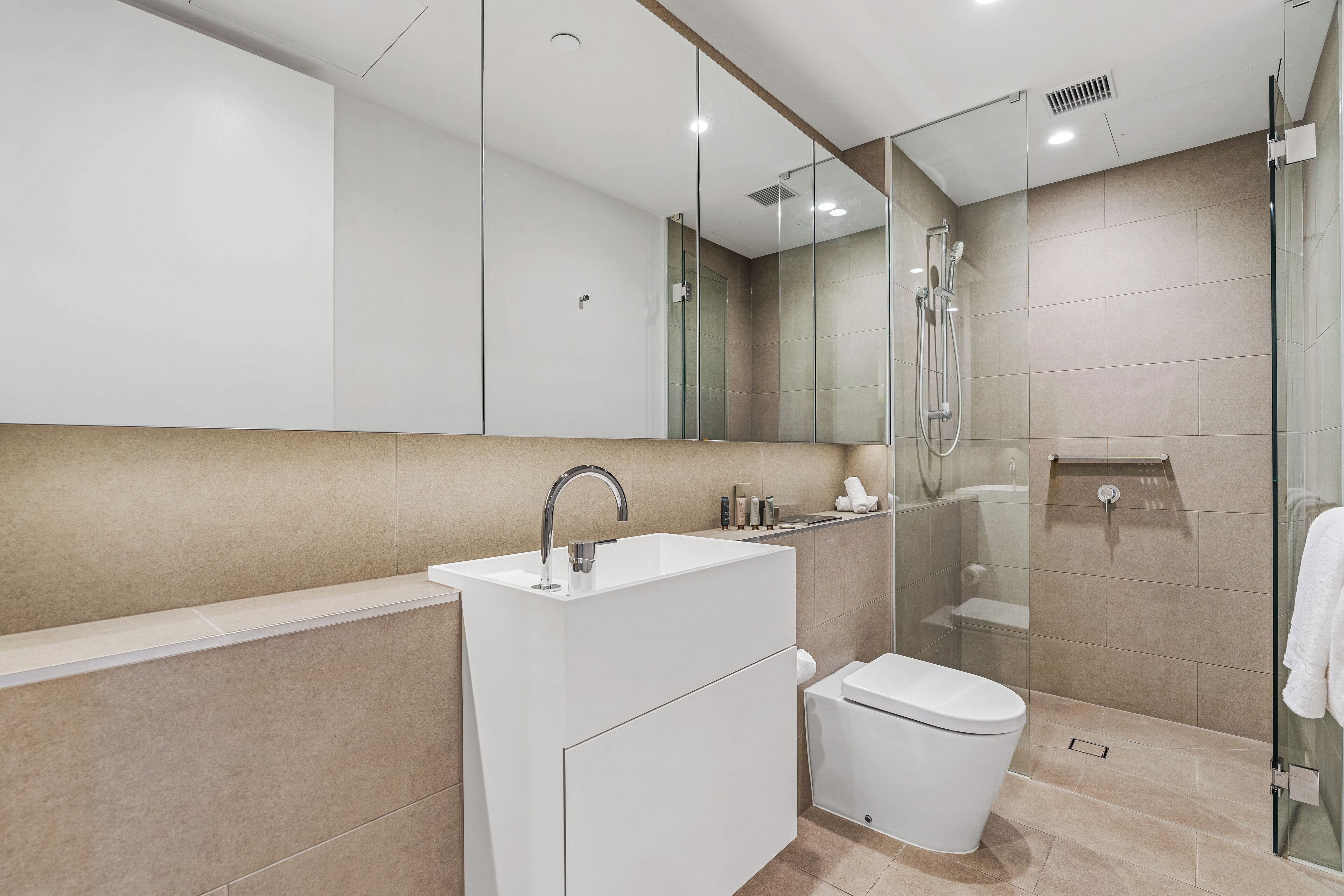 A modern bathroom with a glass-enclosed shower, a white sink, and a toilet.