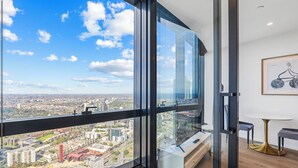 A modern room with a large window offering a city view, a minimalist design, and a small table with a gold base.
