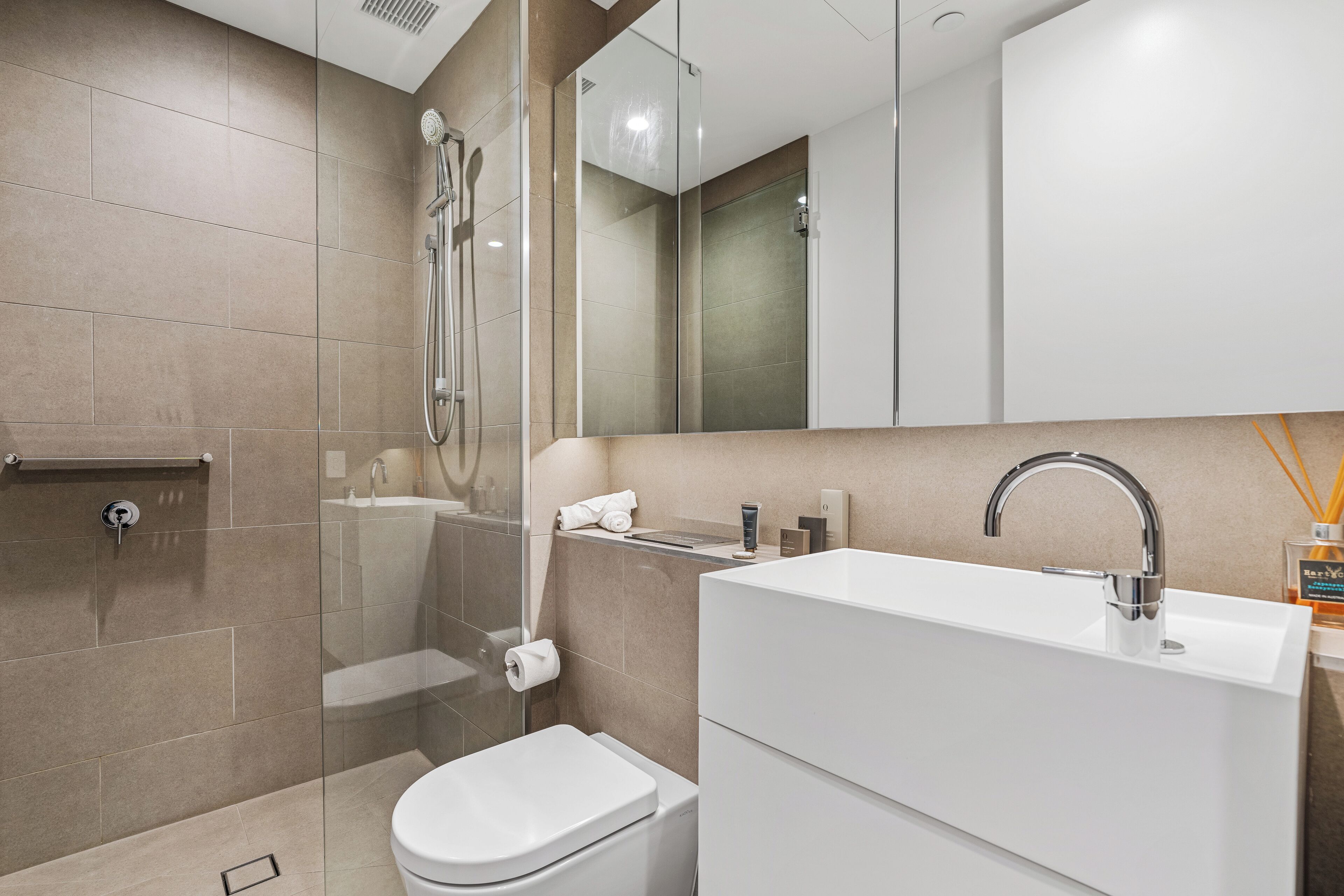 A modern bathroom with a shower, toilet, and sink.