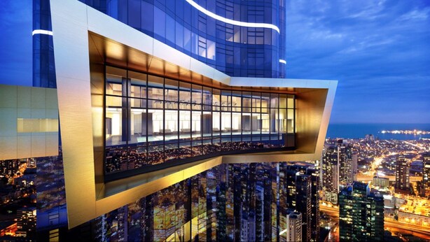 A modern high-rise building with a curved glass facade and a large, illuminated atrium.