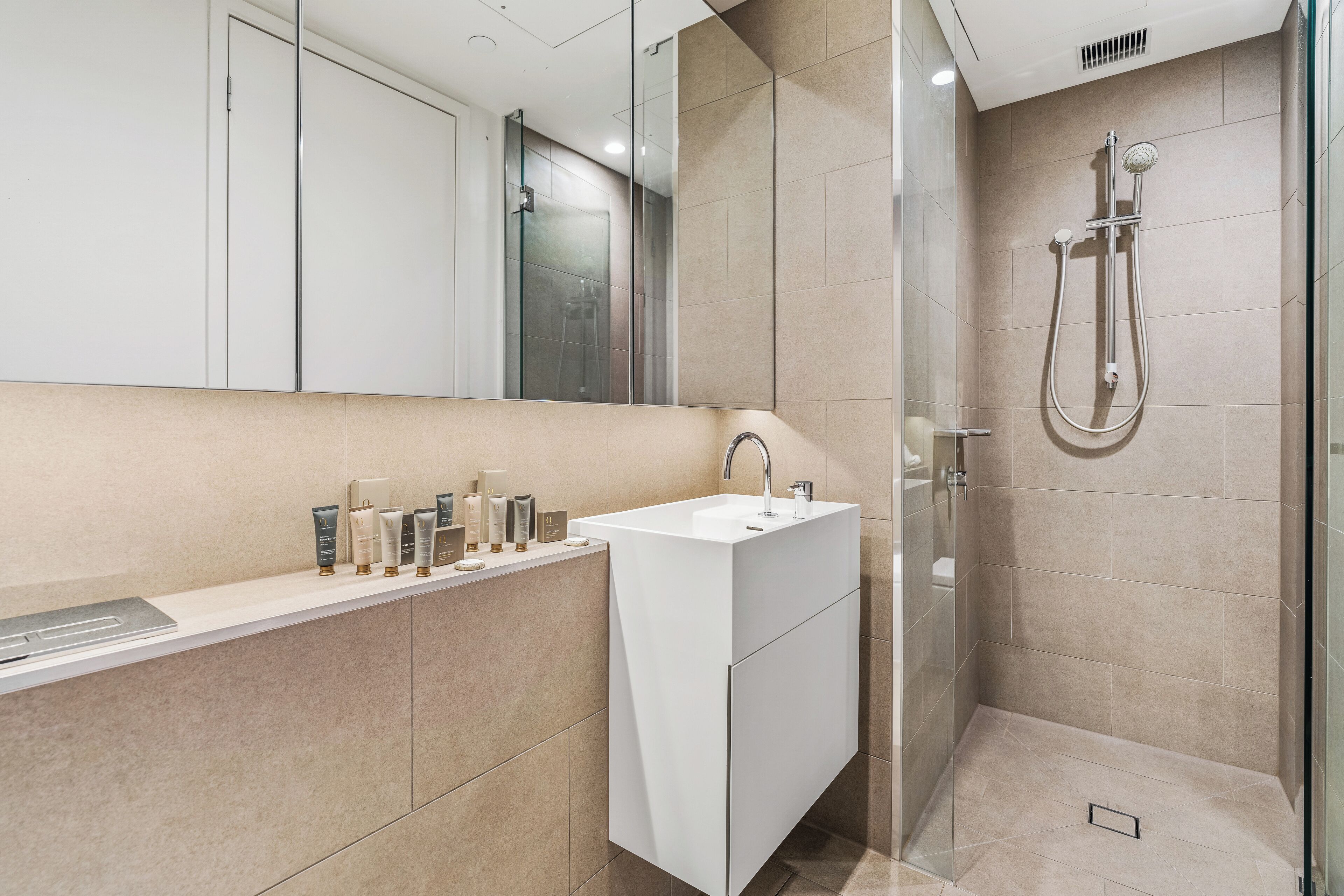 A modern bathroom with a white sink, a glass shower enclosure, and a mirror above the sink.