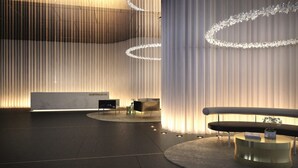 A modern reception area with a marble reception desk, a black sofa, and a round coffee table.
