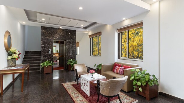 A modern living room with a sofa, chairs, a coffee table, and a fireplace. - Inde Hotel Cyber City (Gurugram)