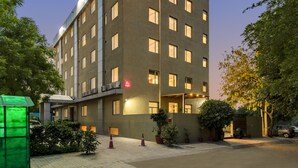 A multi-story hotel with a modern design, featuring a prominent red logo on the top. - Inde Hotel Cyber City (Gurugram)