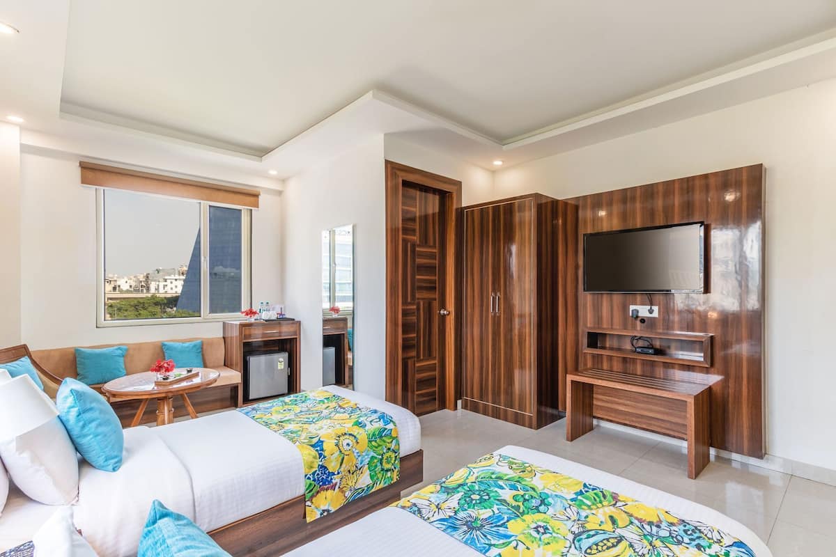 A hotel room with two beds, a desk, a TV, and a wardrobe.