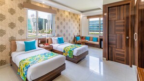 A hotel room with two beds, a sofa, a small table, and a large window offering a city view. - Inde Hotel Cyber City (Gurugram)
