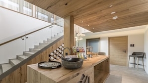 Une cuisine moderne avec un îlot central en bois, un évier intégré et un escalier en verre.