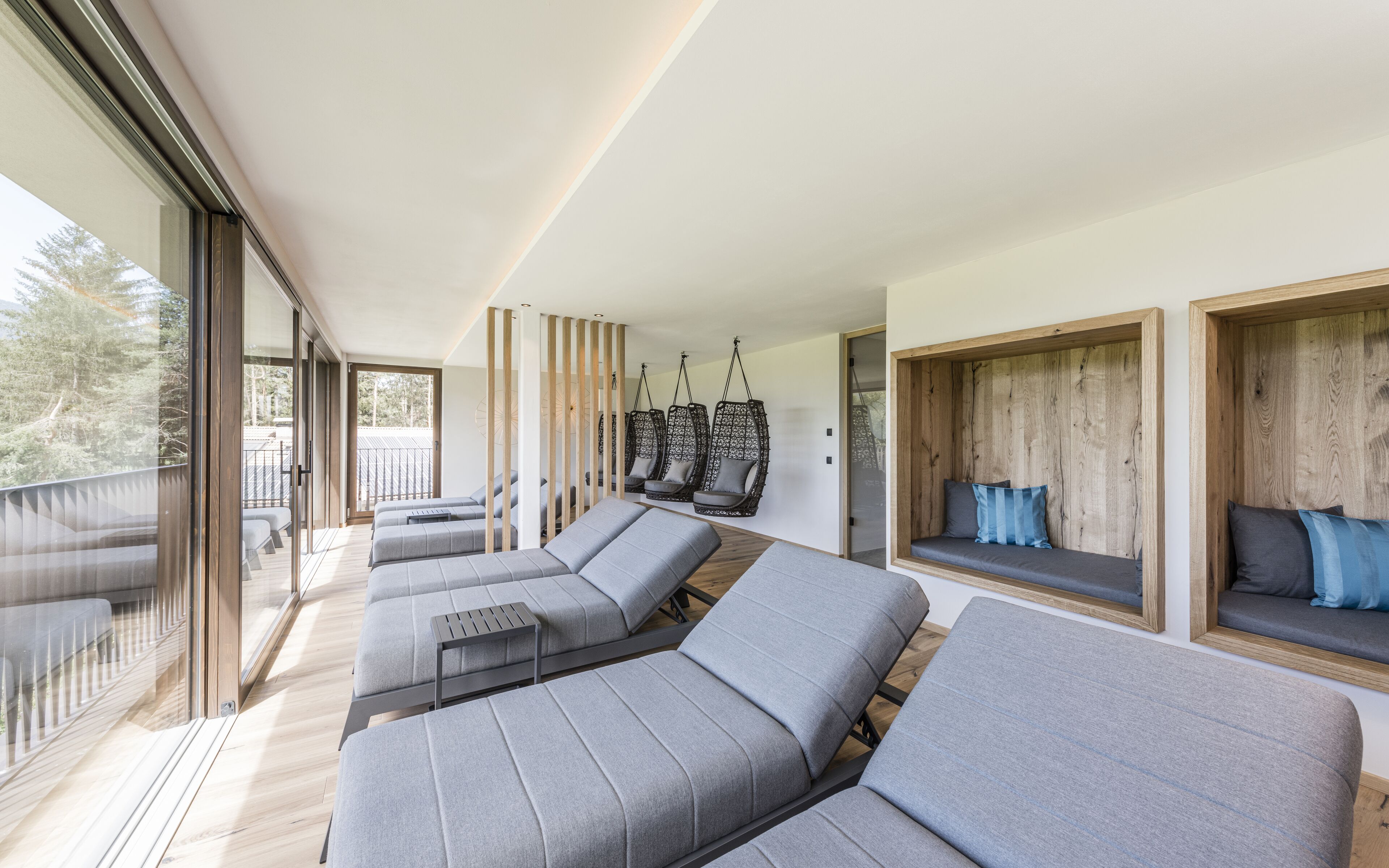 Ein modernes Interieur mit einer langen Reihe grauer Sofas und einer Holzwand mit hängenden Sesseln.