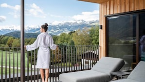 Un balcon avec vue sur des montagnes enneigées, un plafond en bois et une porte vitrée.