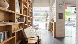 A cozy interior with wooden shelves, a sofa, and a view of the street outside. - Simply Sleep Hostel (Bangkok)