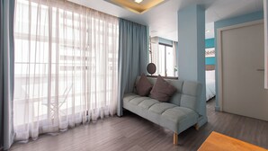 A modern living room with a sofa, a wooden coffee table, and sheer curtains. - Simply Sleep Hostel (Bangkok)