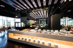 A buffet area with various food stations, a seating area with tables and chairs, and a modern ceiling design with lighting fixtures. - Holiday Garden Hotel SKM Park (Kaohsiung)