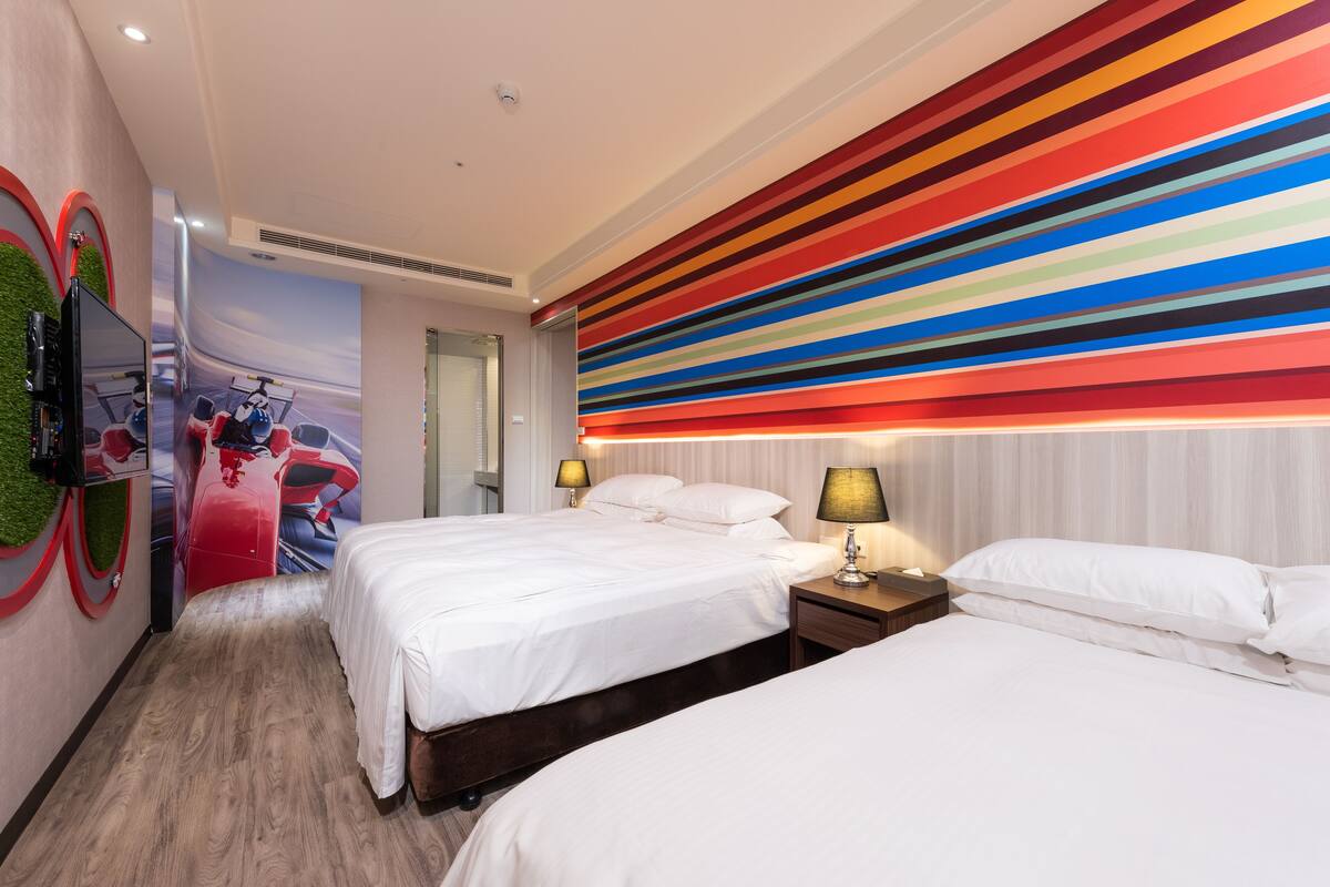Ett hotellrum med två sängar, en tv och en vägg med färgglada ränder.