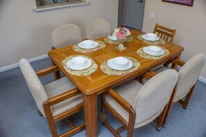 Una mesa de comedor dispuesta con platos, un florero con flores y sillas.