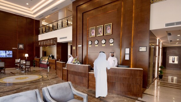 A hotel lobby with a reception desk, seating area, and a TV screen. - Zaha Al Munawara Hotel (Madinah)