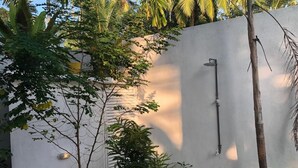 A white wall with a built-in showerhead and a small tree in the foreground. - Villa White (Hikkaduwa)