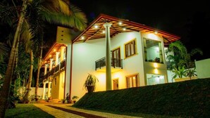 A two-story building with a balcony, surrounded by palm trees and a well-lit exterior. - Villa White (Hikkaduwa)