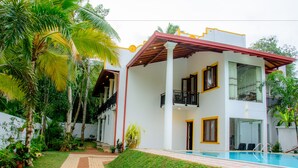 A two-story building with a pool, surrounded by palm trees and a well-maintained lawn. - Villa White (Hikkaduwa)