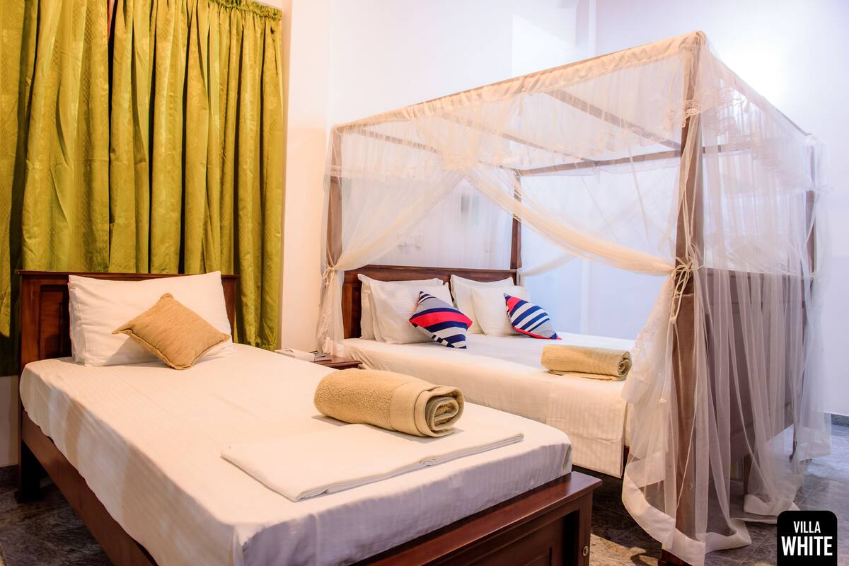 Habitación de hotel con dos camas, una con dosel y la otra sin él.