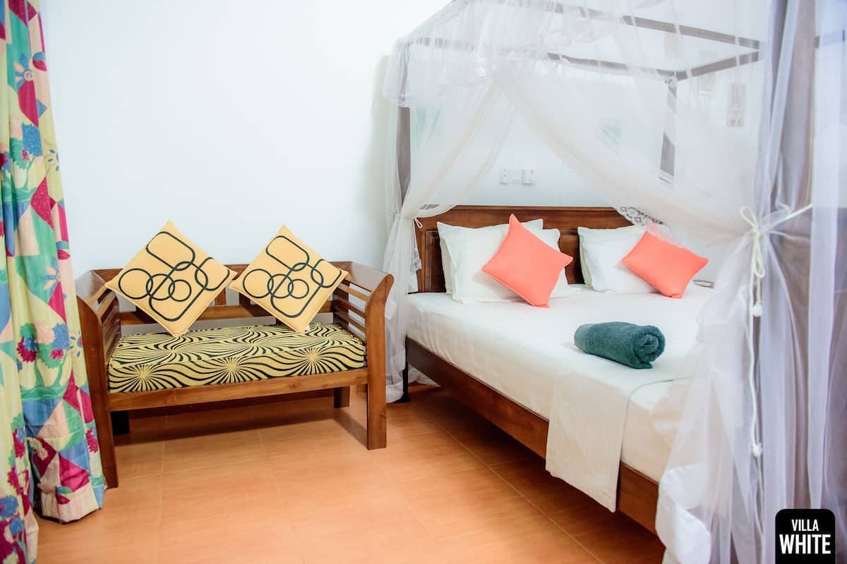 Un dormitorio con cama de madera, una cama tipo diván y una cama con dosel.